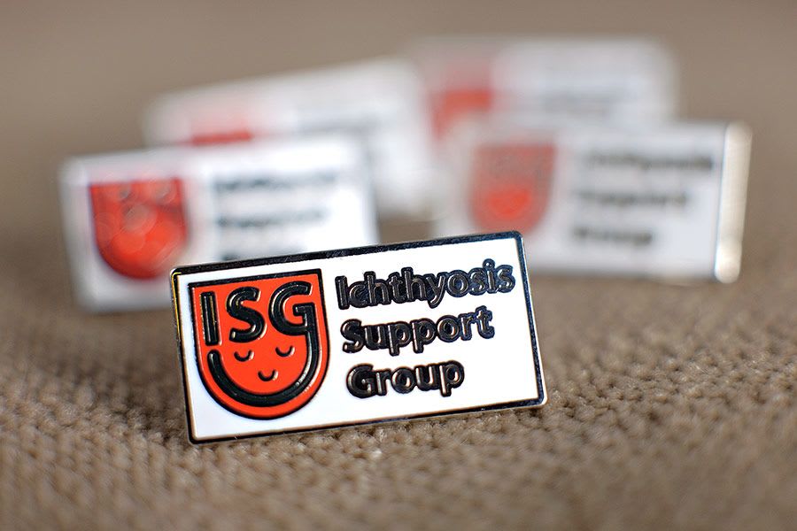 An ISG lapel pin badge with the smiling ISG logo.