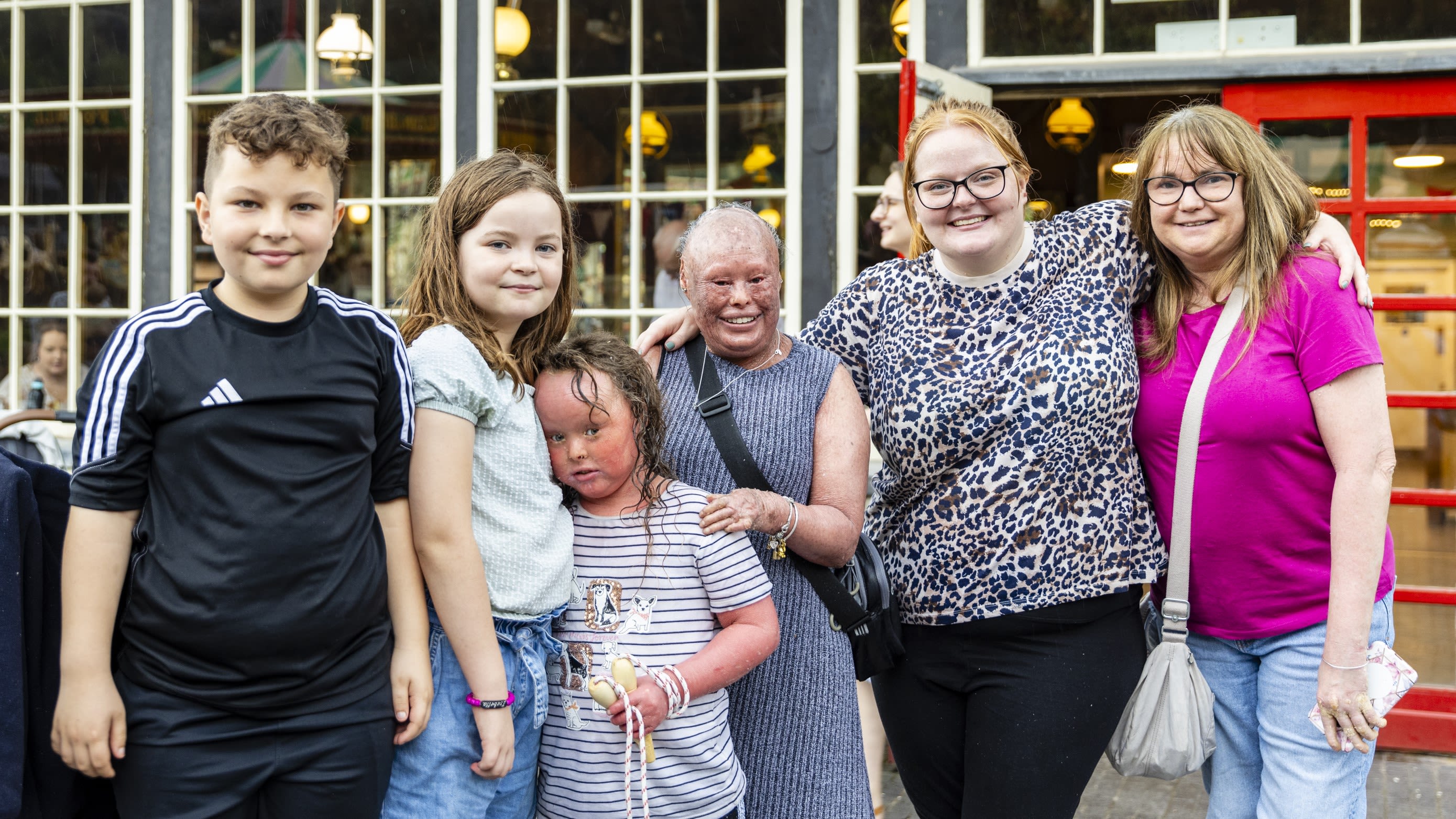 A group of ISG members, parents and children, smiling together outside a café at a member event.